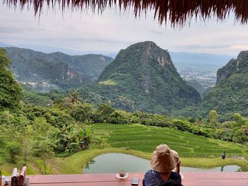 Rear view of woman looking at mountains against sky