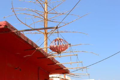 Low angle view of damaged lantern hanging on building against sky