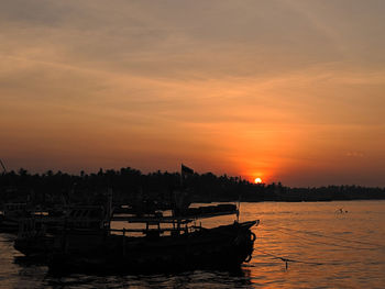 Silhouette boat in sea against sky during sunset