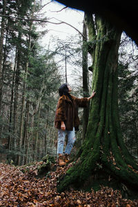 Woman standing by tree trunk