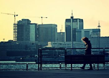 Woman standing on city street at sunset