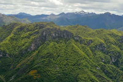 Scenic view of green landscape and mountains against sky