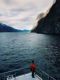 Scenic view of sea by mountain against sky