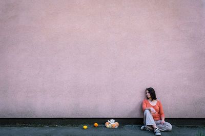 Woman sitting against pink wall