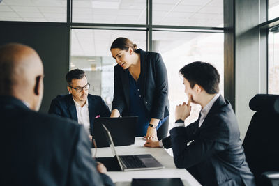 Businesswoman discussing over laptop with colleagues in conference room at office