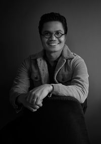 Portrait of smiling young man against black background