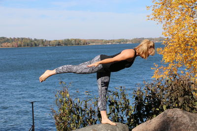 Toppling tree yoga pose by the lake 