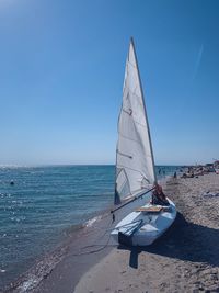 Sailboat on beach against clear blue sky