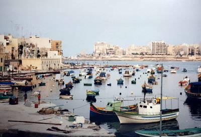 High angle view of boats moored at harbor by buildings against sky