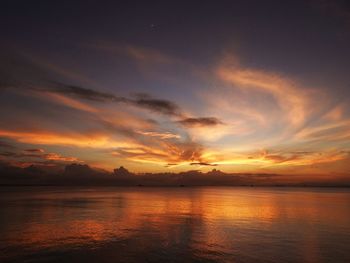 Scenic view of sea against dramatic sky during sunset