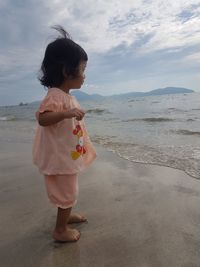 Full length of girl standing at beach against sky