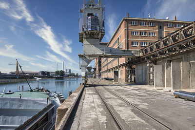 Bridge over river by buildings against sky