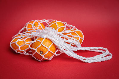 Eco-friendly mesh with tangerines on a red festive background. feast of the nativity of christ.