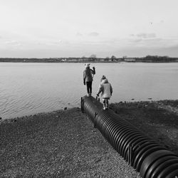 Man and woman looking at sea against sky