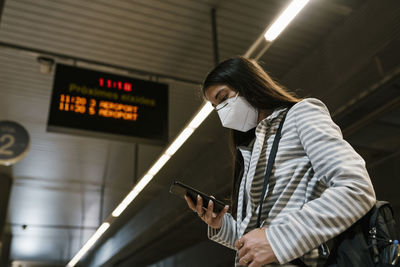 Female passenger using phone while waiting at railroad station