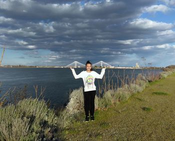 Optical illusion of happy teenage girl lifting cable bridge over columbia river against cloudy sky