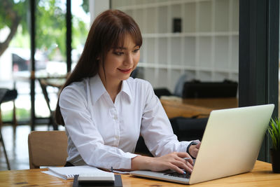 Woman using phone while sitting on table