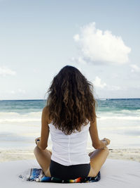Young woman meditation on beach, rear view