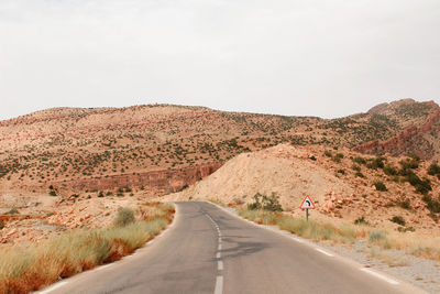 Road leading towards mountain against sky