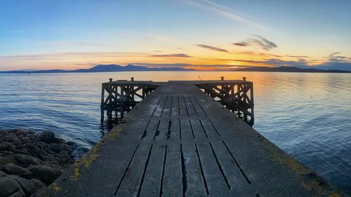 Pier over sea against sky during sunset