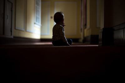 Rear view of child sitting on floor at home