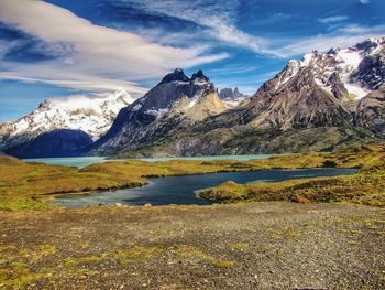 Scenic view of lake by snowcapped mountains against sky