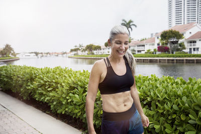 Happy sporty mature woman walking on footpath by canal