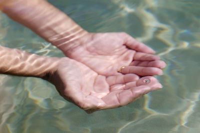 High angle view of hands cupped in sea