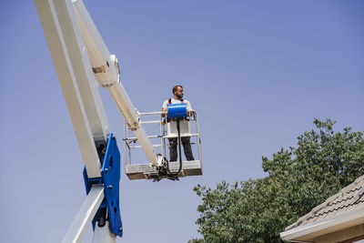 Engineer standing on hydraulic platform by roof