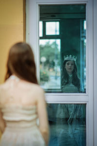 Rear view of woman standing in glass window