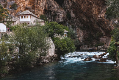 Water flowing through rocks amidst trees and building