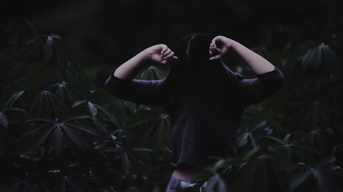 Woman removing t-shirt while standing by plants 