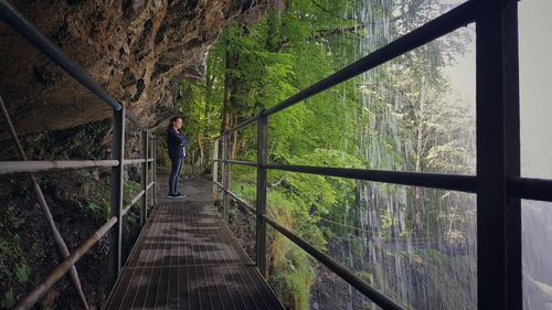 Side view of woman standing on footbridge