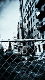 View of buildings seen through chainlink fence