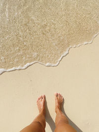 Low section of person standing on sand at beach