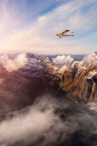 Airplane flying over mountains against sky