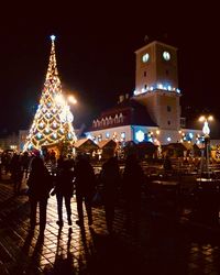 People walking on illuminated building at night