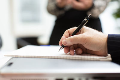 Close-up of man hand holding paper on table