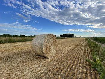 Hay bales on field against sky