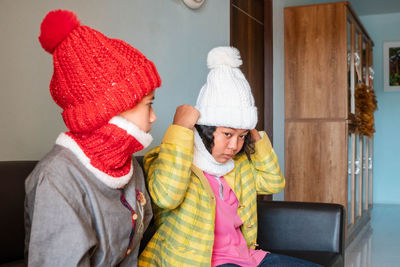 Winter fashion knit hat cute woman sitting on the sofa in the house two people wearing knit hats