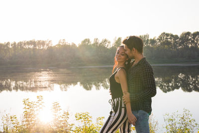 Beautiful woman standing by lake against sky