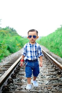 Portrait of cute boy in railroad tracks against sky