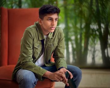 Full length portrait of young man sitting outdoors