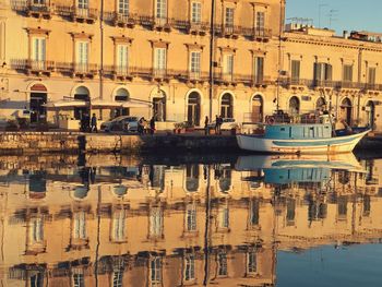 Boats moored in lake against buildings in city