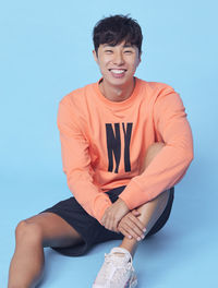 Portrait of smiling woman sitting against blue background