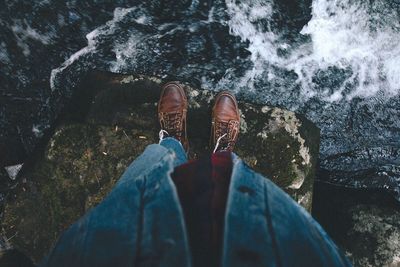 Low section of man standing on rock by river