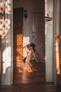 Woman sitting on door of building