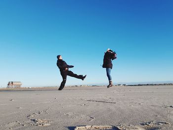 People on beach against clear blue sky