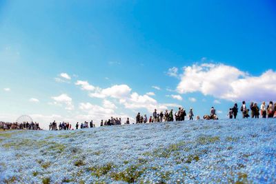 Low angle view of people on field against sky