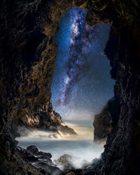 Rock formations in sea against sky at night